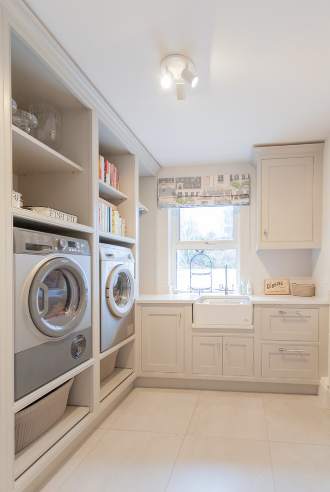 Imagen de armario lavadero en L de tamaño medio con fregadero sobremueble, armarios con paneles empotrados, puertas de armario blancas y lavadora y secadora juntas