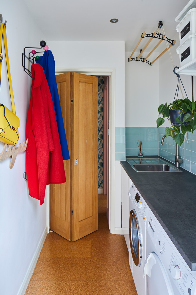 Einzeilige Retro Waschküche mit Einbauwaschbecken, weißer Wandfarbe, Korkboden, Waschmaschine und Trockner nebeneinander und grauer Arbeitsplatte in London