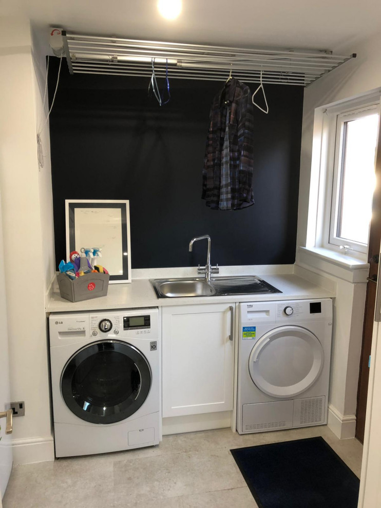 Small traditional single-wall separated utility room in Other with shaker cabinets, white cabinets, composite countertops, white worktops, a single-bowl sink, blue walls, vinyl flooring, a side by side washer and dryer and beige floors.