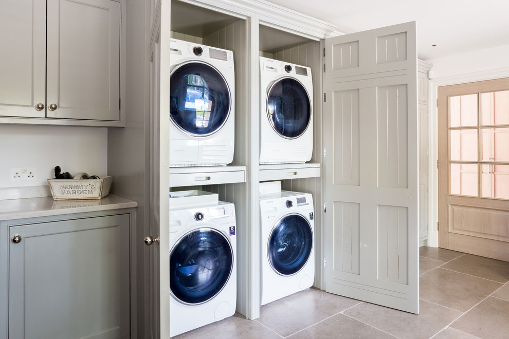 Foto de cuarto de lavado campestre grande con puertas de armario grises, suelo de baldosas de porcelana, lavadora y secadora escondidas, armarios con rebordes decorativos y suelo beige