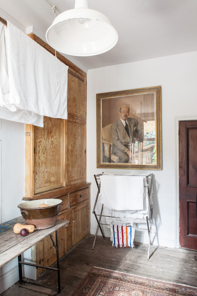 Foto på en eklektisk tvättstuga, med luckor med infälld panel, skåp i ljust trä, träbänkskiva, vita väggar och mörkt trägolv