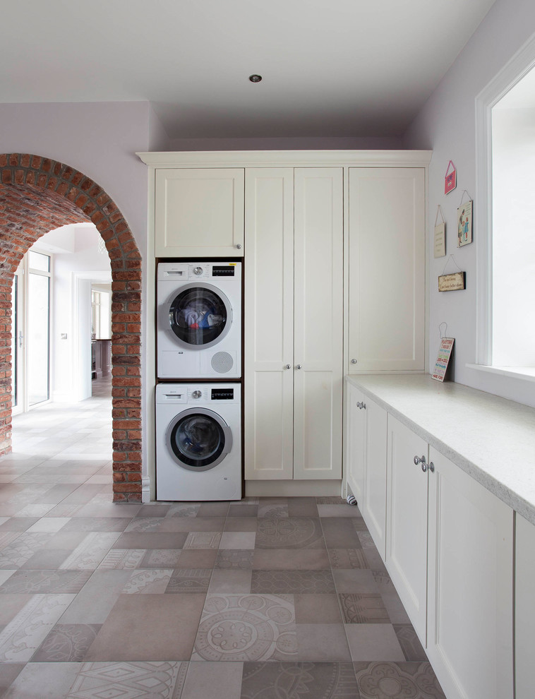 Ispirazione per una lavanderia classica di medie dimensioni con ante in stile shaker, top bianco, ante beige, pareti grigie, lavatrice e asciugatrice a colonna e pavimento grigio