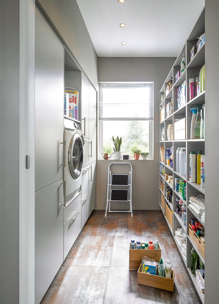 Diseño de lavadero multiusos y de galera contemporáneo con armarios con paneles lisos, puertas de armario blancas, paredes blancas y suelo gris
