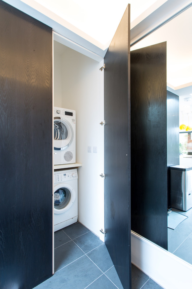 Immagine di un piccolo ripostiglio-lavanderia minimal con pareti bianche, pavimento con piastrelle in ceramica e lavatrice e asciugatrice a colonna