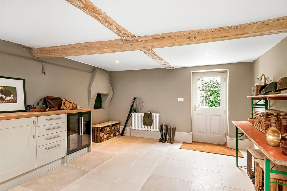 Utility room - mid-sized eclectic single-wall porcelain tile and beige floor utility room idea in Hampshire with recessed-panel cabinets, white cabinets, wood countertops, gray walls and a side-by-side washer/dryer