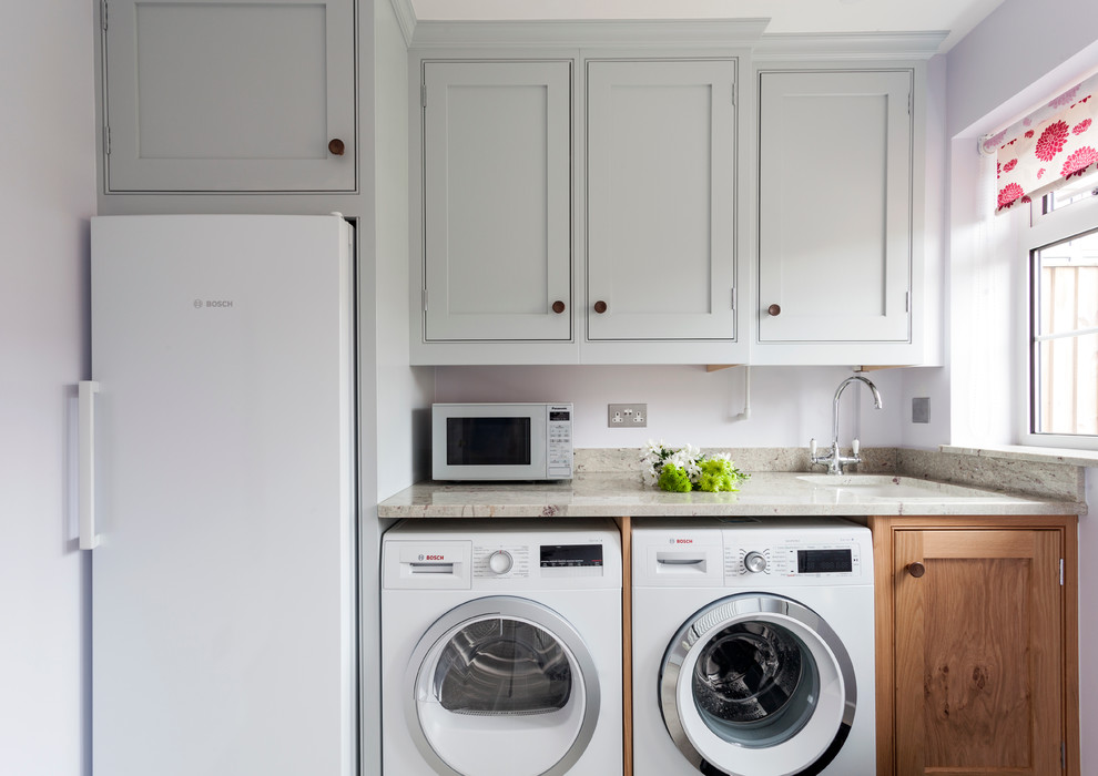 Esempio di una piccola lavanderia tradizionale con ante a filo, top in granito, lavello sottopiano, ante grigie, pareti viola e lavatrice e asciugatrice affiancate