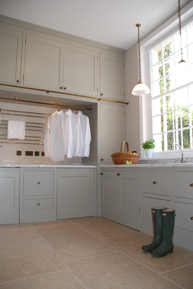Utility room - huge traditional u-shaped limestone floor and beige floor utility room idea in West Midlands with an undermount sink, shaker cabinets, gray cabinets, marble countertops, gray walls, a concealed washer/dryer and white countertops