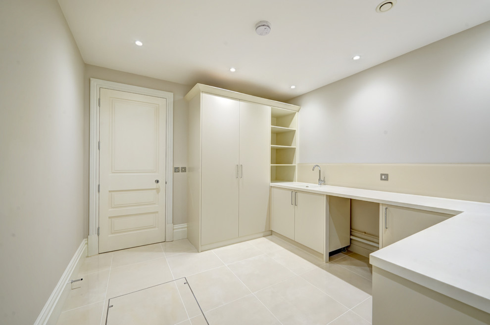 Inspiration for a large contemporary single-wall utility room in London with a built-in sink, flat-panel cabinets, beige cabinets, grey walls and porcelain flooring.
