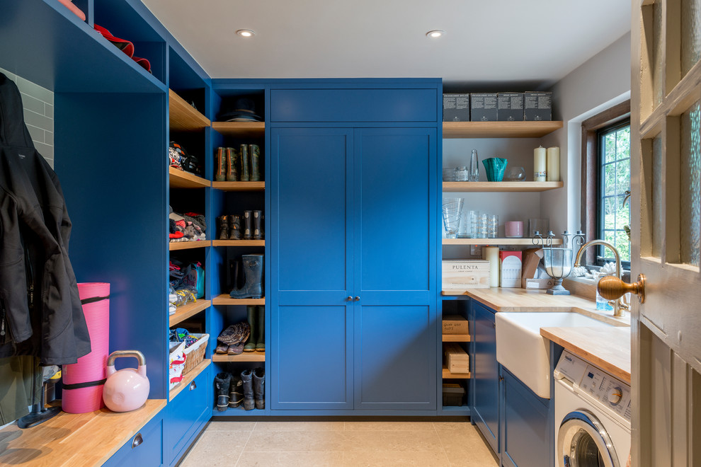 Design ideas for a country u-shaped utility room in Surrey with a belfast sink, shaker cabinets, blue cabinets, wood worktops, yellow walls, beige floors and beige worktops.
