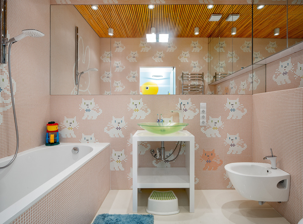 Idéer för funkis badrum för barn, med öppna hyllor, ett badkar i en alkov, en dusch/badkar-kombination, en bidé, mosaik, rosa väggar, ett fristående handfat och flerfärgad kakel