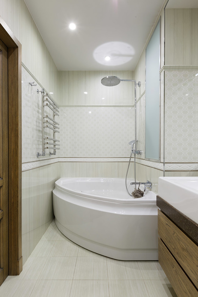 Свежая идея для дизайна: главная ванная комната в современном стиле с плоскими фасадами, фасадами цвета дерева среднего тона, угловой ванной, бежевой плиткой и монолитной раковиной - отличное фото интерьера