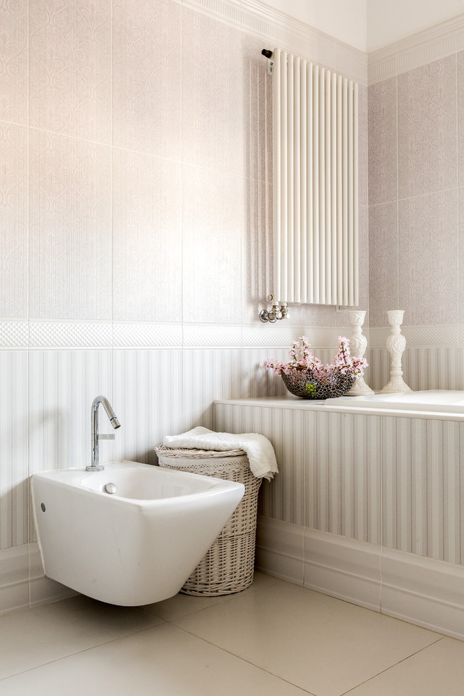 Aménagement d'une salle de bain romantique avec une baignoire posée, un bidet et un mur rose.