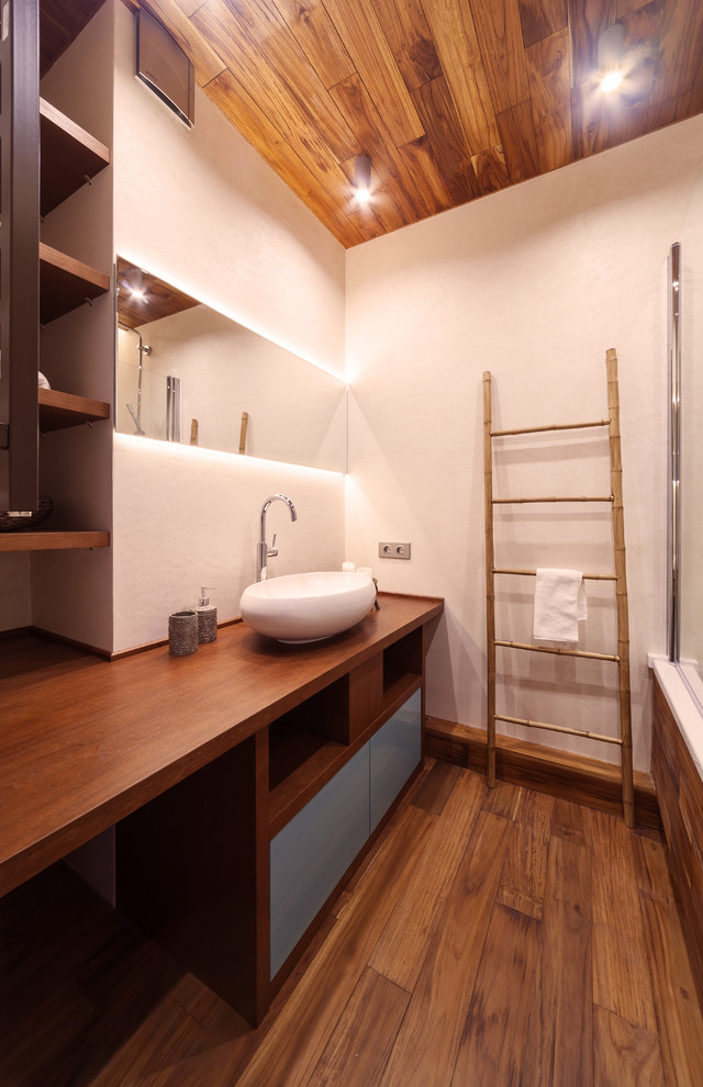 Esempio di una stanza da bagno padronale minimal di medie dimensioni con ante lisce, ante turchesi, pareti bianche, pavimento in laminato, lavabo da incasso, top in legno e pavimento marrone
