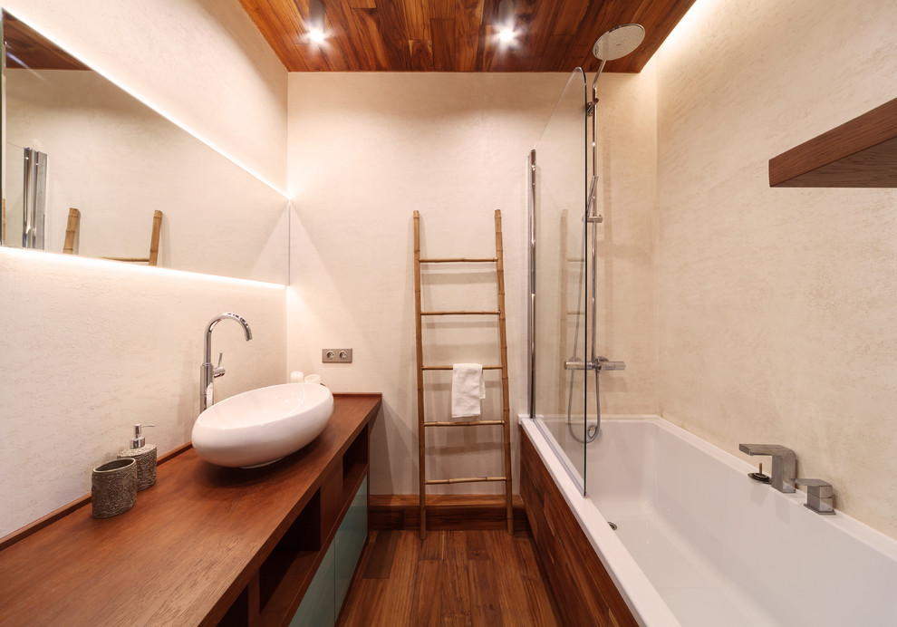 Inspiration för mellanstora moderna en-suite badrum, med beige väggar, träbänkskiva, ett fristående handfat, släta luckor, turkosa skåp, ett badkar i en alkov, målat trägolv och brunt golv