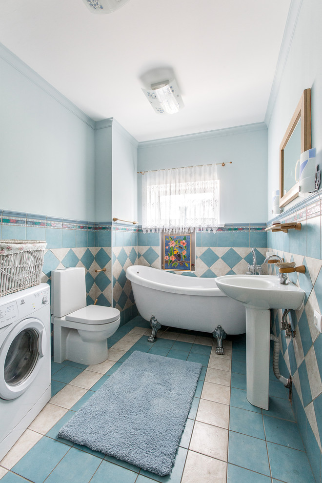 Diseño de cuarto de baño principal clásico con bañera con patas, combinación de ducha y bañera, sanitario de dos piezas, baldosas y/o azulejos azules, baldosas y/o azulejos blancos, paredes azules y lavabo con pedestal