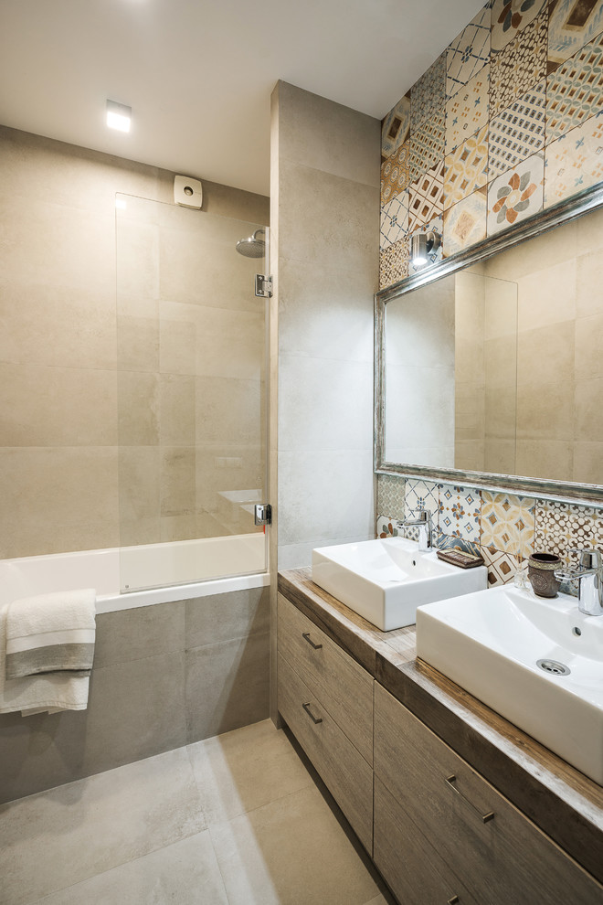 Mid-sized trendy master brown tile and porcelain tile porcelain tile and beige floor bathroom photo in Other with flat-panel cabinets, dark wood cabinets, a wall-mount toilet, beige walls, a drop-in sink and tile countertops