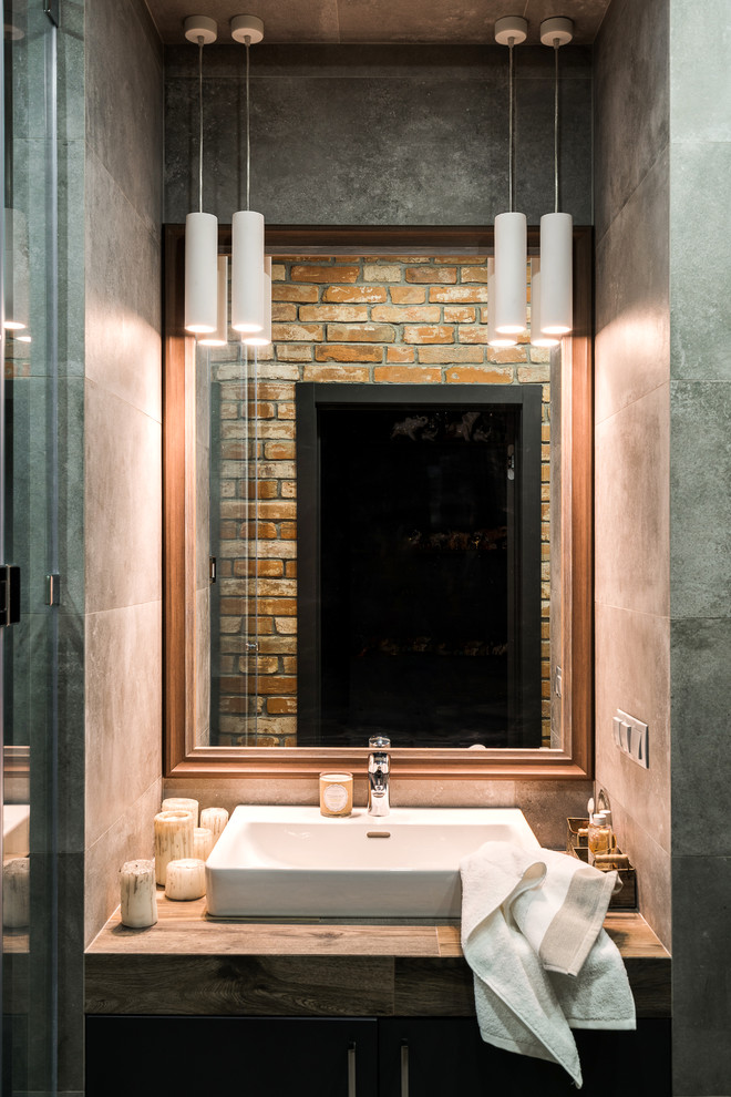 Photo of a medium sized industrial shower room bathroom in Other with glass-front cabinets, dark wood cabinets, a built-in shower, a wall mounted toilet, brown tiles, porcelain tiles, grey walls, porcelain flooring, a built-in sink, tiled worktops, grey floors and a hinged door.