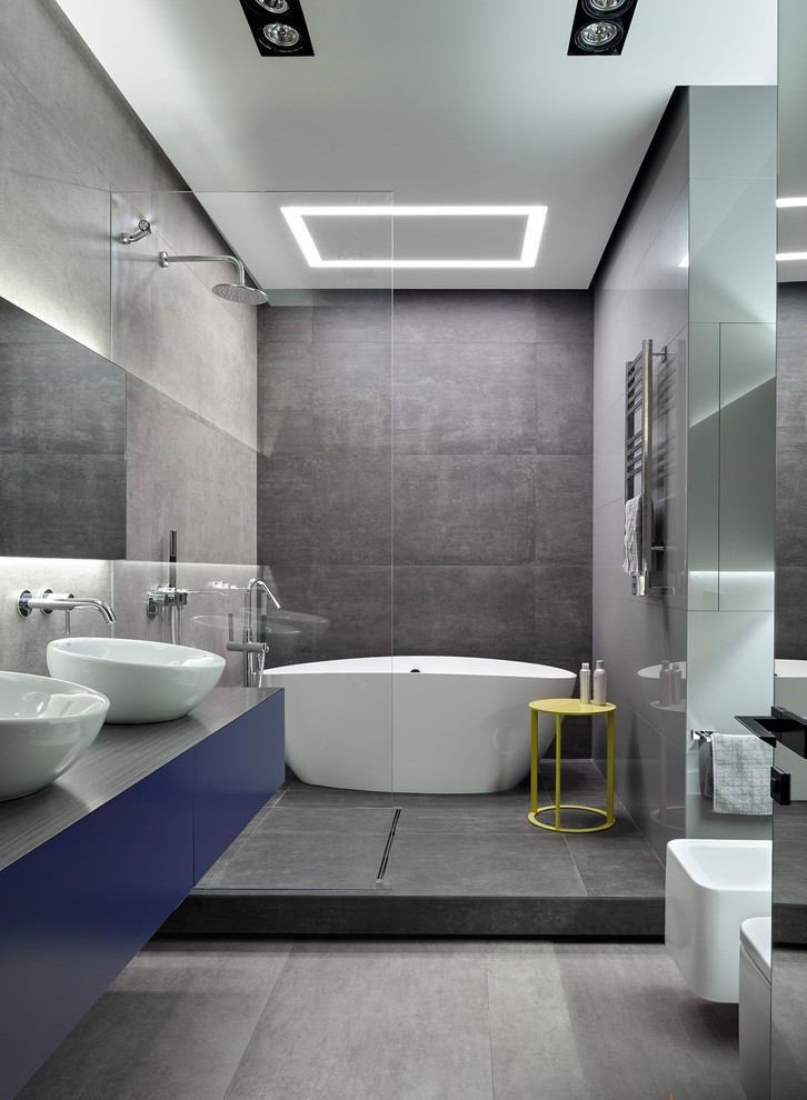 Пример оригинального дизайна: главная ванная комната в современном стиле с душевой комнатой, плоскими фасадами, синими фасадами, отдельно стоящей ванной, инсталляцией, серой плиткой, настольной раковиной и открытым душем