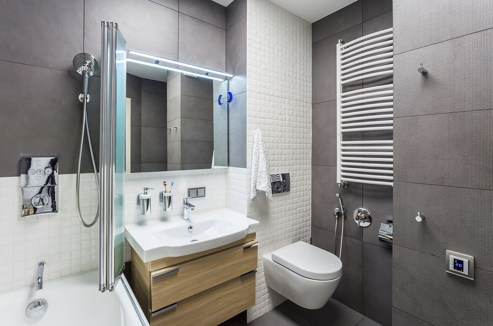 Пример оригинального дизайна: главная ванная комната среднего размера в современном стиле с инсталляцией, серой плиткой, белой плиткой, плоскими фасадами, светлыми деревянными фасадами, душем над ванной, монолитной раковиной, серым полом и гигиеническим душем