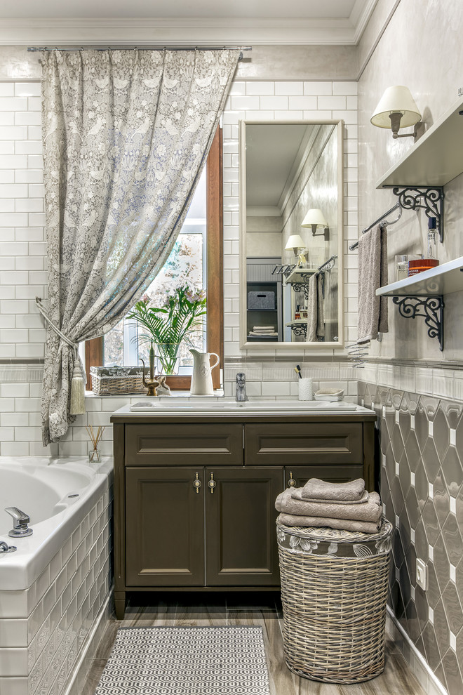 На фото: главная ванная комната среднего размера: освещение в классическом стиле с фасадами с утопленной филенкой, коричневыми фасадами, белой плиткой, серой плиткой, накладной раковиной и бежевым полом с