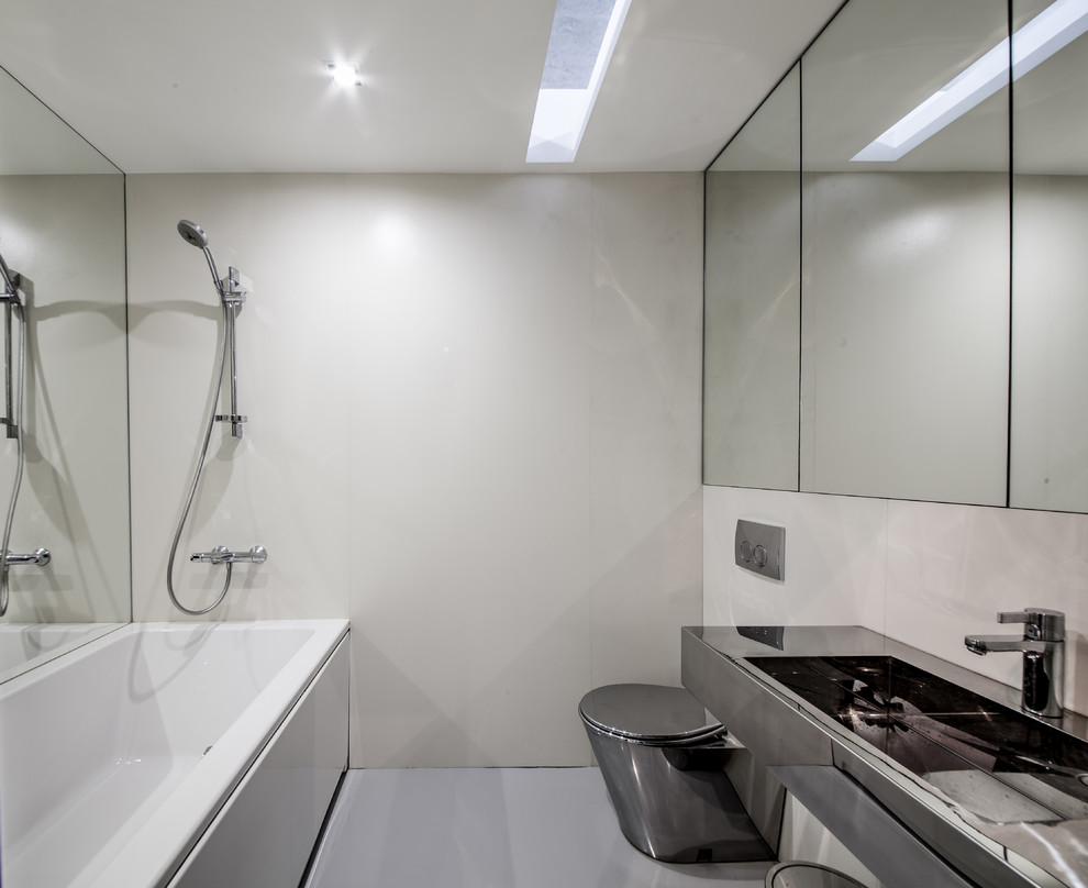 Small contemporary ensuite bathroom in Yekaterinburg with grey cabinets, concrete flooring, grey floors, an alcove bath, beige tiles, porcelain tiles, a wall-mounted sink, stainless steel worktops and a two-piece toilet.