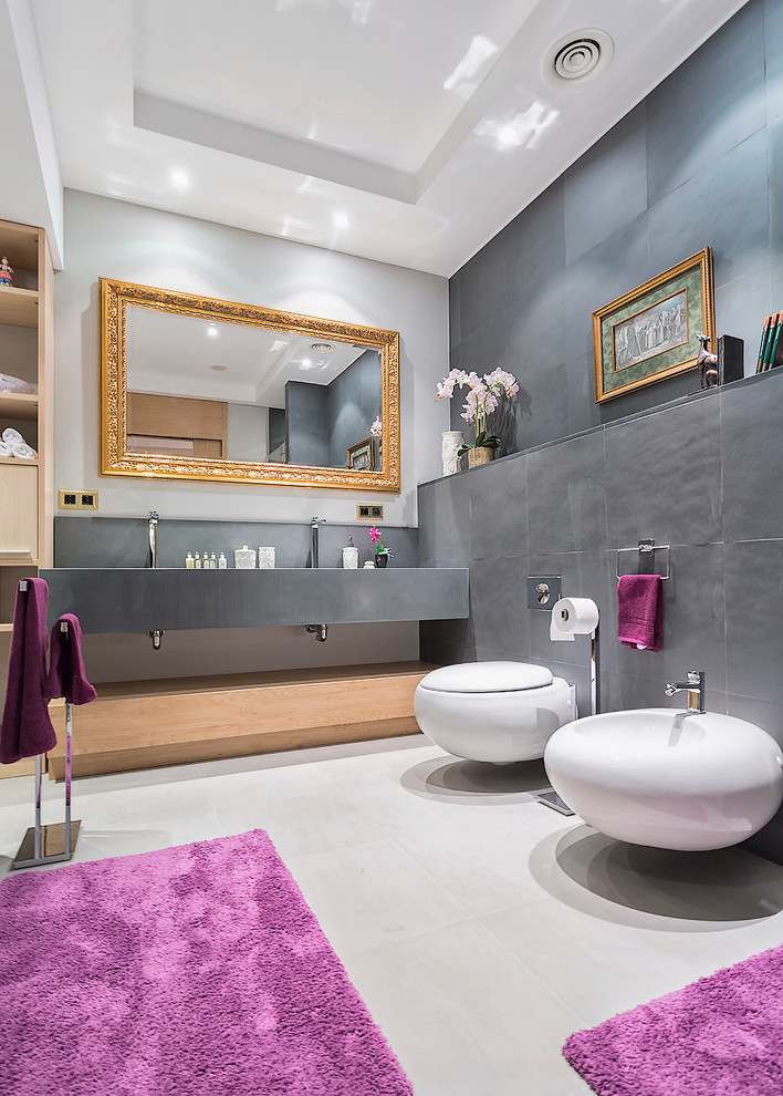 Immagine di una stanza da bagno design con bidè, piastrelle grigie, pareti multicolore e lavabo sottopiano