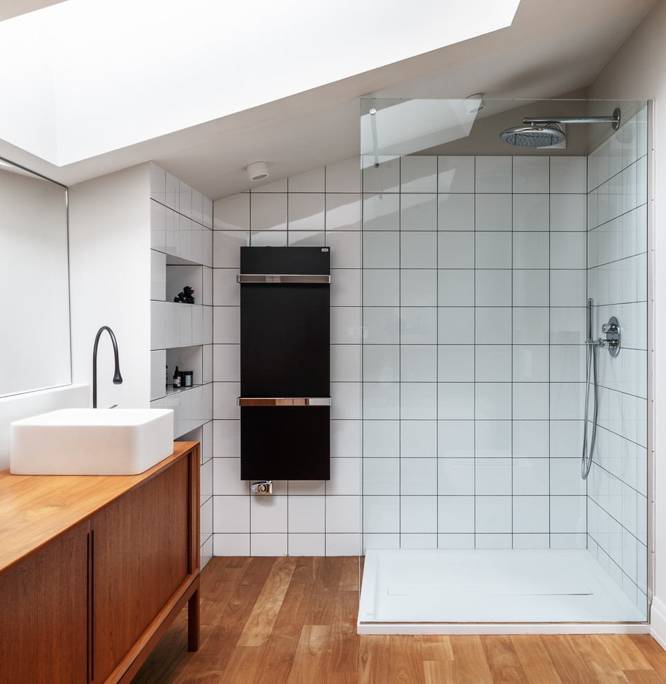 На фото: ванная комната в современном стиле с фасадами цвета дерева среднего тона, угловым душем, белой плиткой, паркетным полом среднего тона, настольной раковиной, столешницей из дерева и плоскими фасадами с