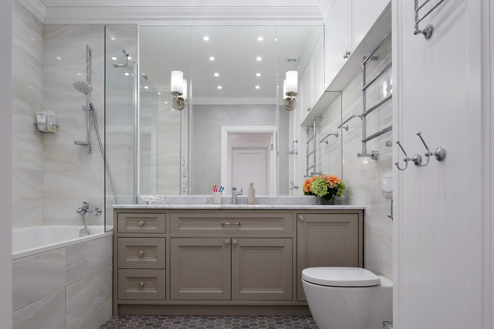 Exemple d'une salle de bain principale et beige et blanche chic avec un placard avec porte à panneau encastré, des portes de placard grises, un combiné douche/baignoire, un carrelage gris, un sol gris, aucune cabine, un plan de toilette gris, une baignoire en alcôve et WC séparés.