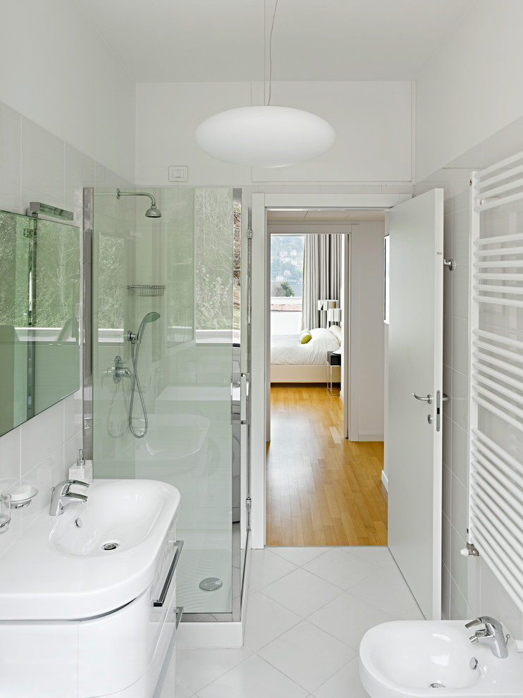 Inspiration för mellanstora moderna badrum med dusch, med släta luckor, vita skåp, vit kakel, keramikplattor, vita väggar, klinkergolv i keramik, ett integrerad handfat, en hörndusch och en vägghängd toalettstol