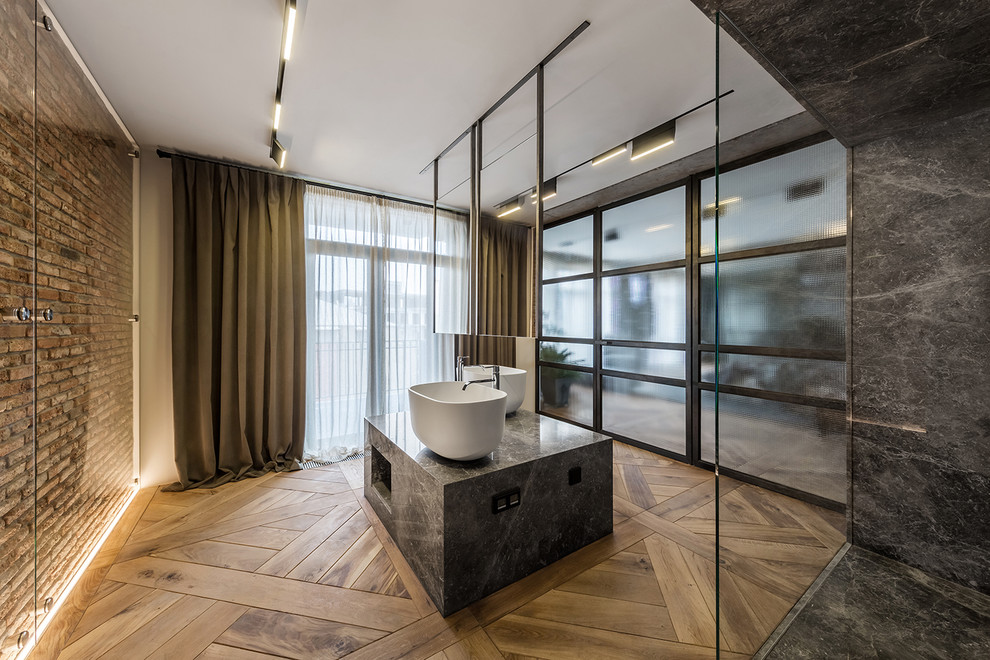 Exemple d'une salle de bain principale industrielle avec une douche à l'italienne, un carrelage noir, un carrelage gris, un mur beige, un sol en bois brun, une vasque, un sol marron, aucune cabine et un plan de toilette gris.