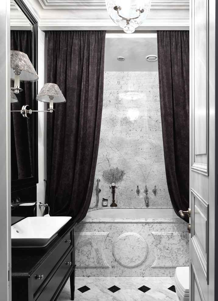 Foto de cuarto de baño principal, tradicional, de tamaño medio, con armarios con paneles empotrados, puertas de armario negras, bañera empotrada, combinación de ducha y bañera, paredes grises y lavabo sobreencimera