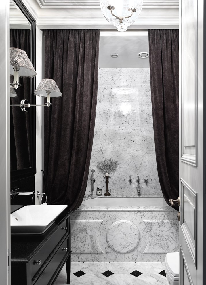 Idée de décoration pour une salle de bain principale tradition de taille moyenne avec un placard avec porte à panneau encastré, des portes de placard noires, une baignoire en alcôve, un combiné douche/baignoire, un mur gris et une vasque.