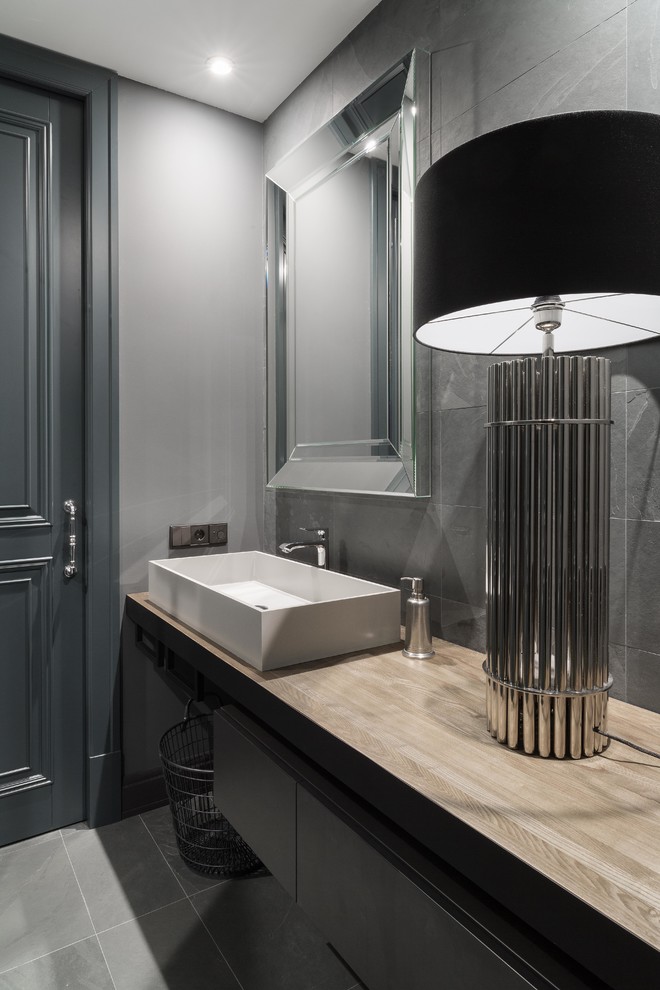 На фото: ванная комната в современном стиле с ванной в нише, серой плиткой, серыми стенами, настольной раковиной и серым полом