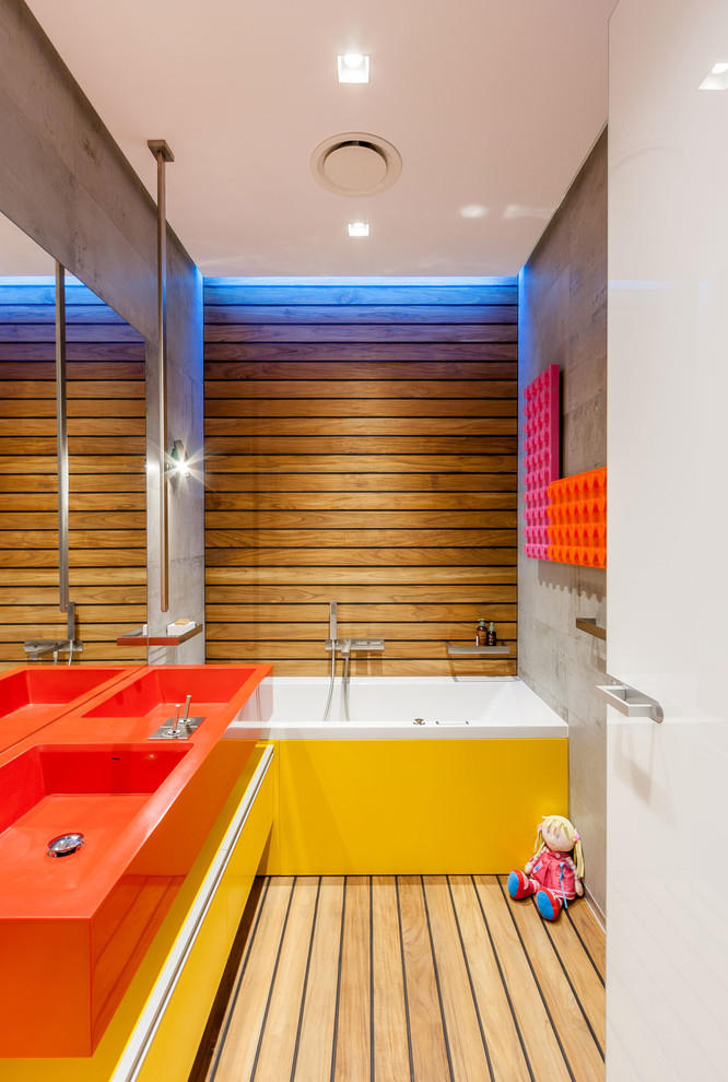 他の地域にあるコンテンポラリースタイルのおしゃれな子供用バスルーム (一体型シンク、フラットパネル扉のキャビネット、黄色いキャビネット、アルコーブ型浴槽、淡色無垢フローリング) の写真
