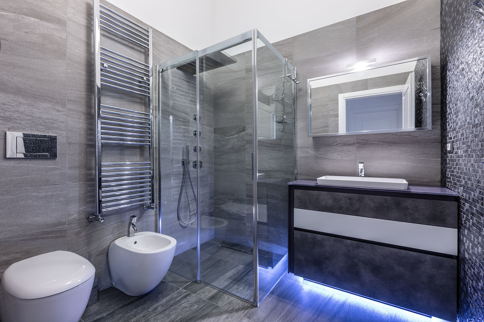Idéer för mellanstora funkis badrum med dusch, med släta luckor, grå skåp, en hörndusch, grå kakel, stenhäll, vita väggar, klinkergolv i porslin, ett avlångt handfat, bänkskiva i glas och dusch med skjutdörr