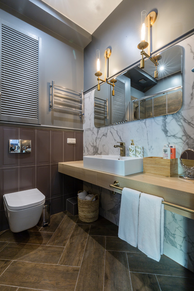 Esempio di una stanza da bagno contemporanea con WC sospeso, piastrelle grigie, piastrelle bianche, pareti grigie, lavabo a bacinella, pavimento marrone e top beige