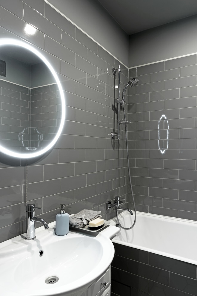 Пример оригинального дизайна: главная ванная комната в стиле неоклассика (современная классика) с белыми фасадами, ванной в нише, душем над ванной, серой плиткой, серыми стенами, плиткой кабанчик, консольной раковиной и зеркалом с подсветкой