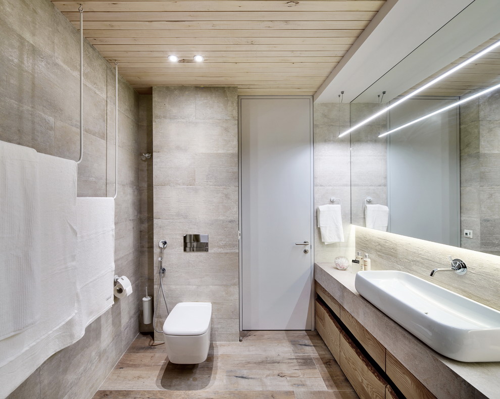 На фото: ванная комната в современном стиле с плоскими фасадами, фасадами цвета дерева среднего тона, инсталляцией, серыми стенами и настольной раковиной с