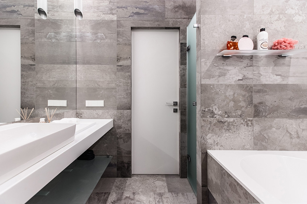 Cette photo montre une salle de bain tendance de taille moyenne avec une baignoire en alcôve, un carrelage gris, des carreaux de porcelaine, un sol en carrelage de porcelaine, un sol gris, une vasque et une cabine de douche à porte battante.