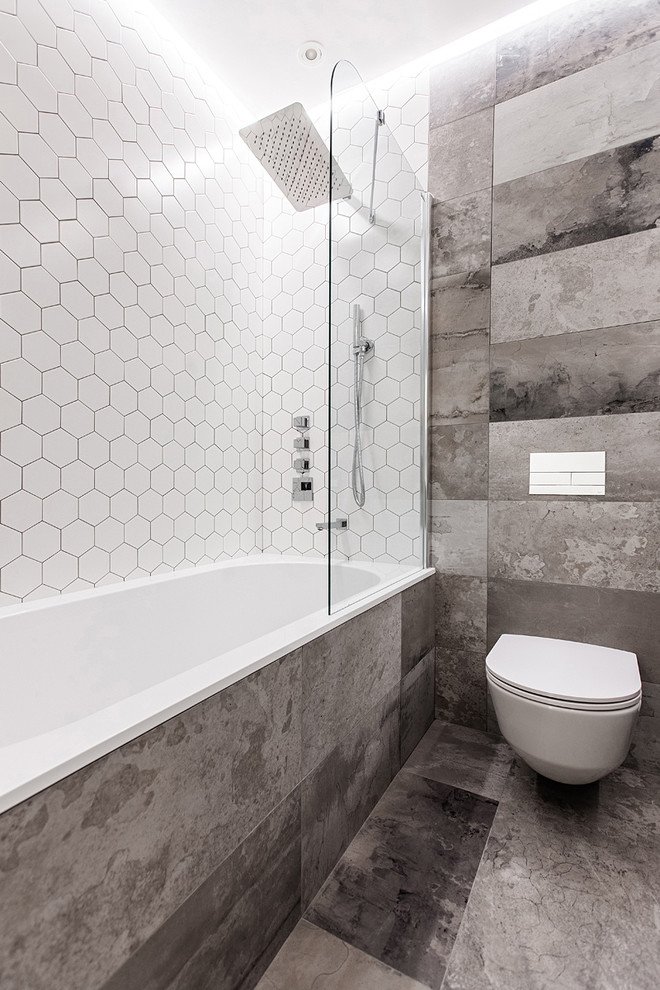 Ejemplo de cuarto de baño principal actual de tamaño medio con bañera empotrada, sanitario de pared, baldosas y/o azulejos grises, baldosas y/o azulejos de porcelana, suelo de baldosas de porcelana y suelo gris