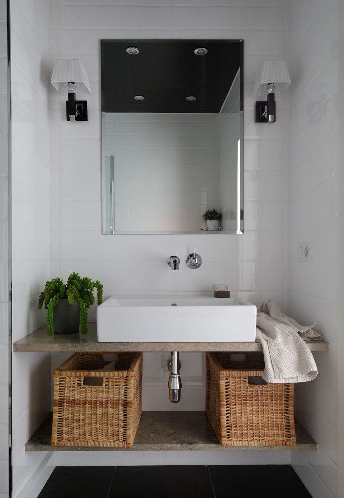 Diseño de cuarto de baño actual con armarios abiertos, baldosas y/o azulejos blancos, lavabo sobreencimera, suelo negro y encimeras beige