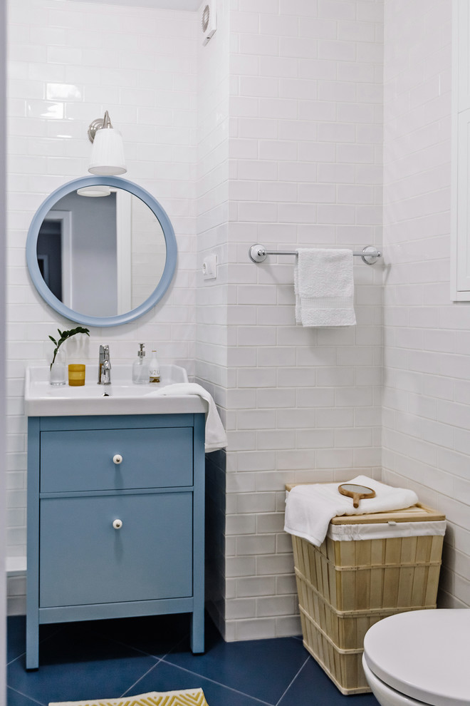 Kleines Nordisches Badezimmer mit flächenbündigen Schrankfronten, blauen Schränken, Wandtoilette, weißen Fliesen, Keramikfliesen, Keramikboden, blauem Boden und integriertem Waschbecken in Sonstige