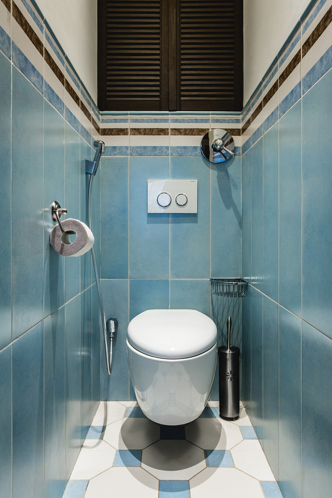 Modern inredning av ett badrum, med en vägghängd toalettstol, blå kakel, vit kakel och flerfärgad kakel