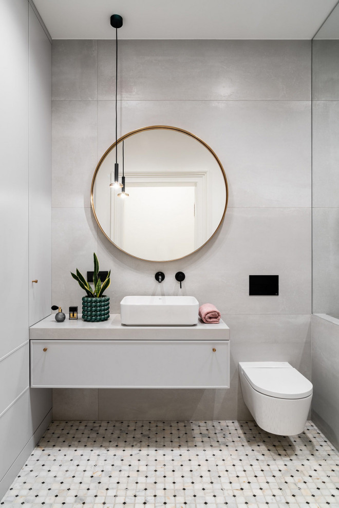 На фото: ванная комната в современном стиле с плоскими фасадами, белыми фасадами, серой плиткой, полом из мозаичной плитки, настольной раковиной, серой столешницей, тумбой под одну раковину и подвесной тумбой с