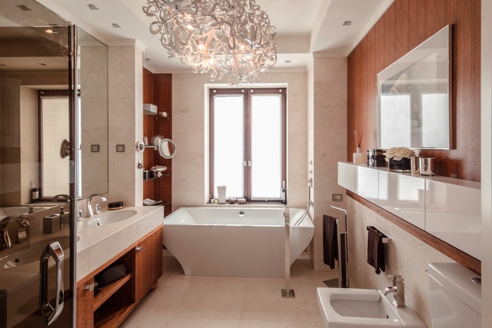 Idée de décoration pour une salle de bain principale design en bois brun avec un placard à porte plane, une baignoire indépendante, un bidet, un lavabo encastré, un sol beige, un mur beige et un plan de toilette beige.
