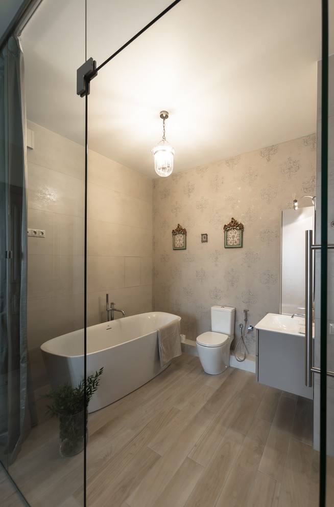 Foto di una stanza da bagno contemporanea con vasca freestanding, WC a due pezzi, piastrelle beige, pareti beige e lavabo integrato