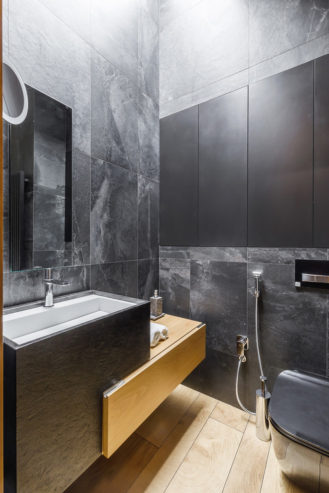 Modern inredning av ett badrum, med grå kakel, ett undermonterad handfat och brunt golv