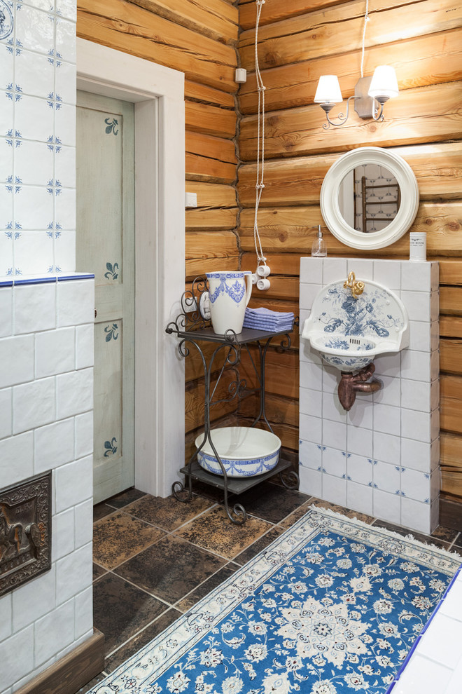 Immagine di una stanza da bagno country con piastrelle blu, piastrelle bianche, piastrelle in ceramica, pareti marroni, pavimento in gres porcellanato e lavabo sospeso