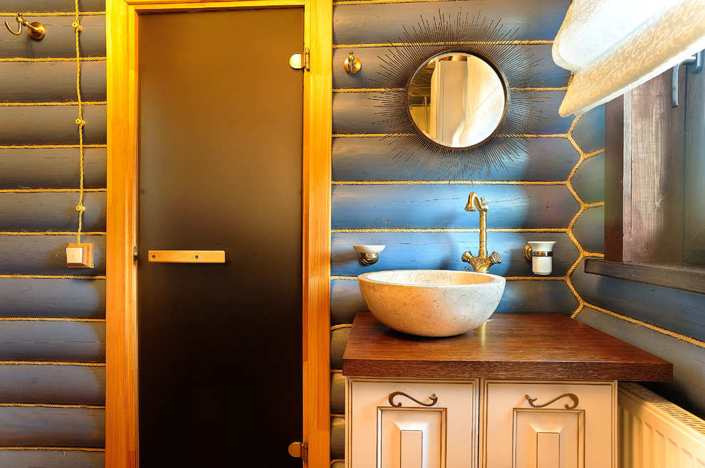 Стильный дизайн: ванная комната в деревянном доме в стиле рустика с синими стенами, настольной раковиной, столешницей из дерева и фасадами с выступающей филенкой - последний тренд