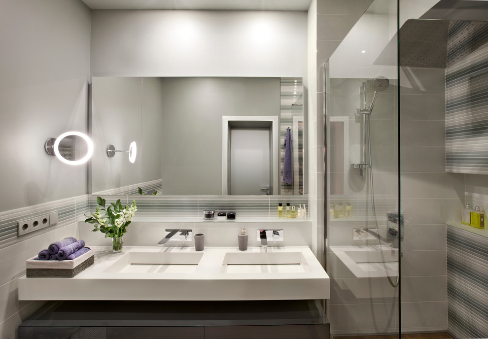 Modern inredning av ett badrum, med grå väggar, ett integrerad handfat och med dusch som är öppen